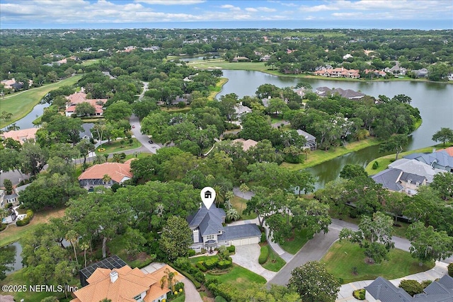 aerial view of property's location featuring a large body of water, nearby suburban area, and a tree filled landscape