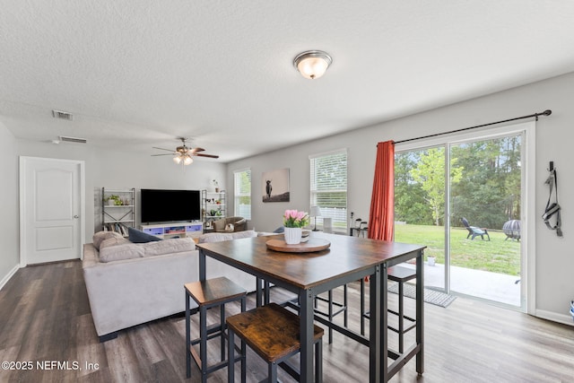 dining area featuring dark wood-style flooring, a ceiling fan, a textured ceiling, and baseboards