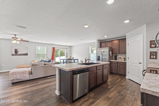 kitchen featuring appliances with stainless steel finishes, a sink, light countertops, dark wood-type flooring, and a textured ceiling