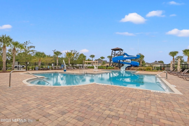 community pool with fence, a patio, and a water slide