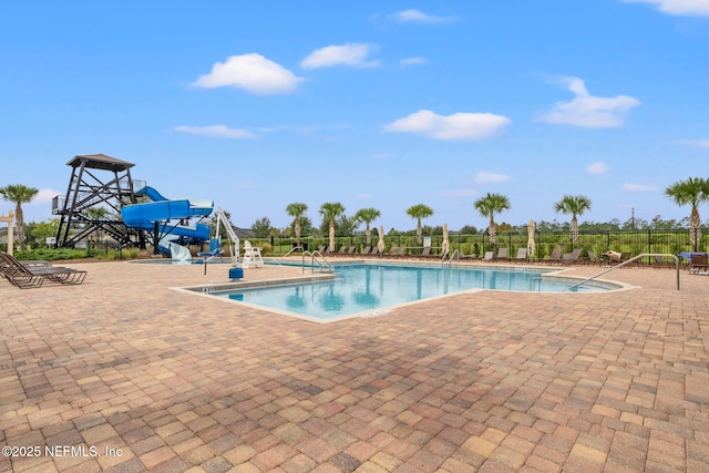 community pool with fence, a patio, and a water slide
