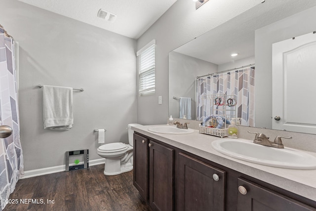 bathroom with toilet, wood finished floors, double vanity, baseboards, and a shower with curtain