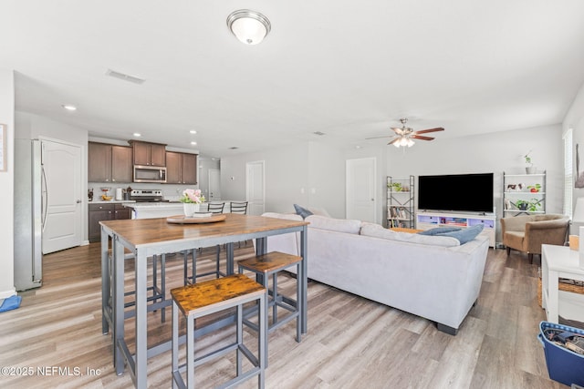 living room featuring light wood-style floors, a ceiling fan, and recessed lighting