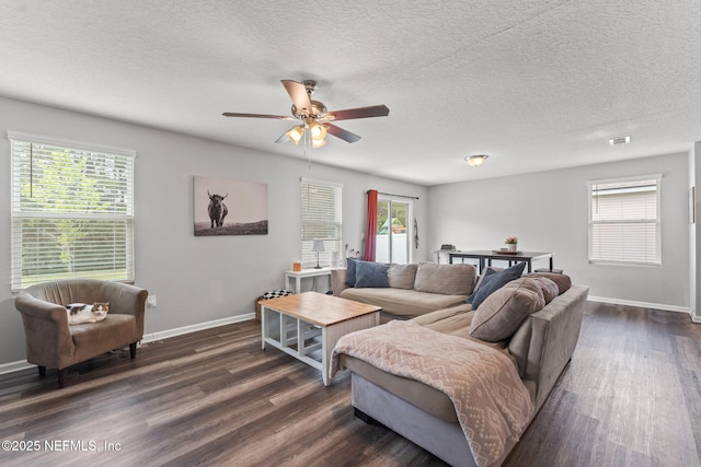 living area with dark wood-style flooring, a ceiling fan, healthy amount of natural light, baseboards, and a textured ceiling