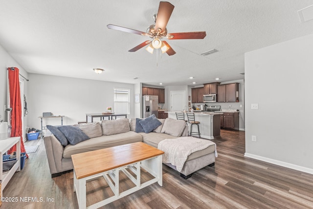 living area featuring dark wood-style flooring, a ceiling fan, baseboards, a textured ceiling, and recessed lighting
