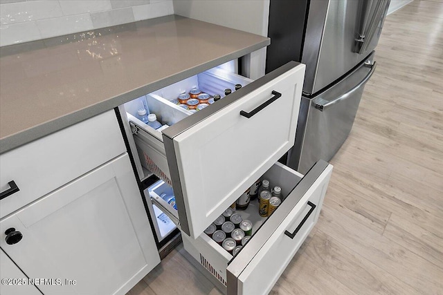 kitchen view of light wood-type flooring, white cabinets, and dark countertops