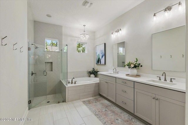 full bath featuring a garden tub, a stall shower, double vanity, a chandelier, and tile patterned flooring