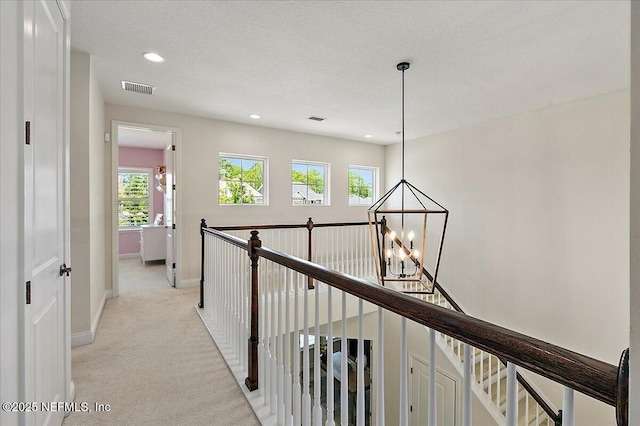 hallway with baseboards, light colored carpet, a chandelier, recessed lighting, and an upstairs landing