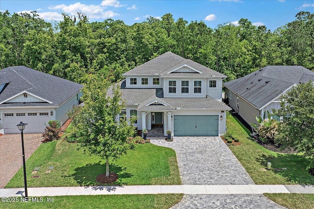 view of front of property with a front yard, decorative driveway, and a garage