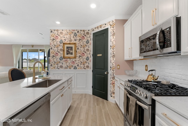 321 Varner Way, Saint Augustine, FL 32092 - kitchen featuring stainless steel appliances, a sink, white cabinetry, wainscoting, and a decorative wall