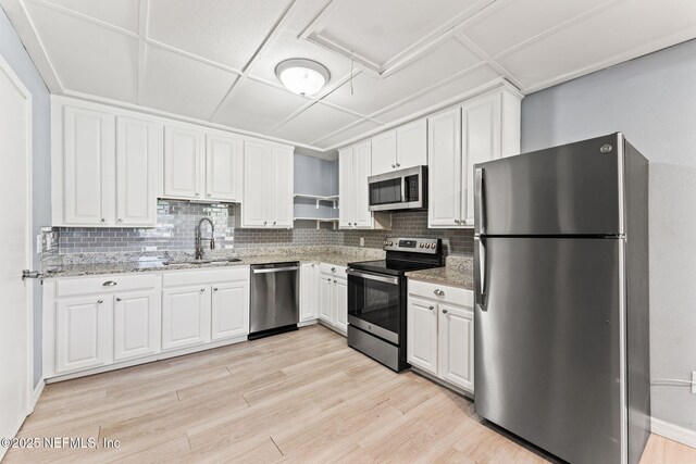 2617 Lake Shore Blvd, Jacksonville, FL 32210 - kitchen featuring stainless steel appliances, a sink, decorative backsplash, open shelves, and light wood-style floors