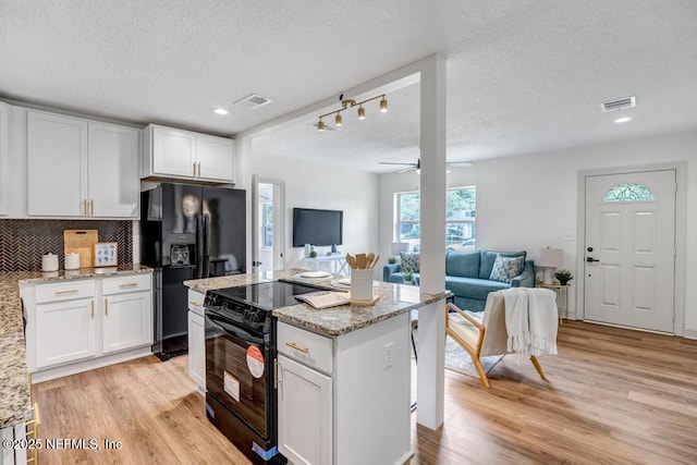 5530 Sharon Ter, Jacksonville, FL 32207 - kitchen with black appliances, white cabinets, light wood-type flooring, light stone counters, and a textured ceiling