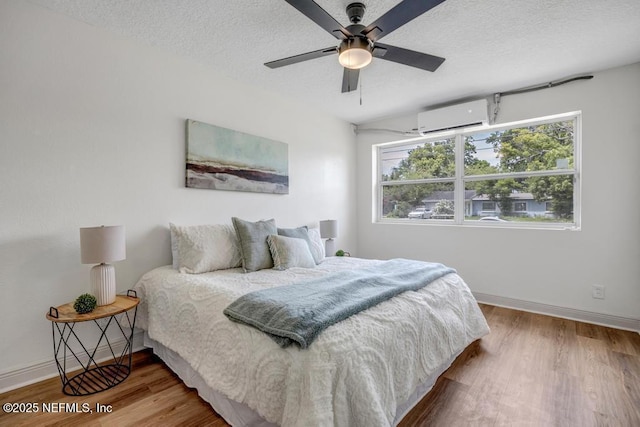 5530 Sharon Ter, Jacksonville, FL 32207 - bedroom with a wall unit AC, wood finished floors, a textured ceiling, baseboards, and a ceiling fan