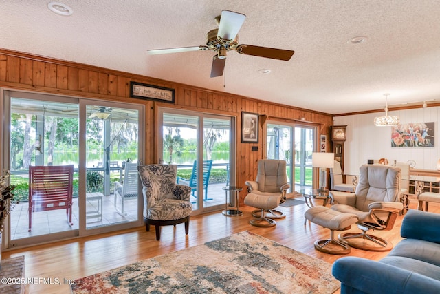 130 Woodbury Trl, Satsuma, FL 32189 - living room featuring a textured ceiling, a chandelier, wood walls, ornamental molding, and wood finished floors