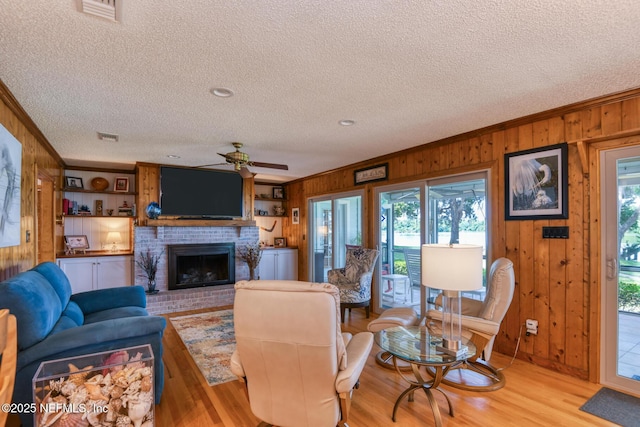 130 Woodbury Trl, Satsuma, FL 32189 - living room featuring wood walls, ceiling fan, a textured ceiling, light wood finished floors, and a fireplace