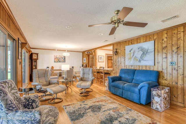 130 Woodbury Trl, Satsuma, FL 32189 - living room featuring ornamental molding, wooden walls, wood finished floors, a textured ceiling, and a chandelier