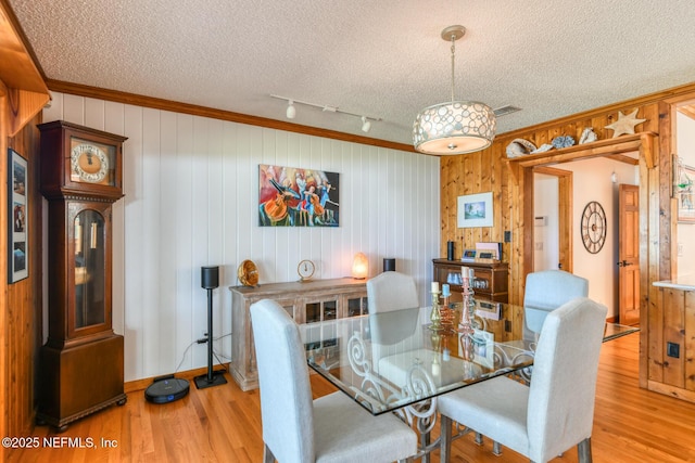 130 Woodbury Trl, Satsuma, FL 32189 - dining space featuring a textured ceiling, light wood-style floors, wooden walls, crown molding, and rail lighting