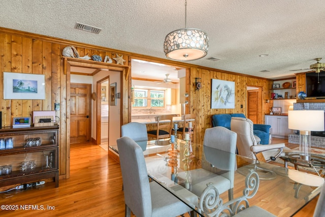 130 Woodbury Trl, Satsuma, FL 32189 - dining area featuring ornamental molding, wooden walls, a ceiling fan, a textured ceiling, and light wood-type flooring