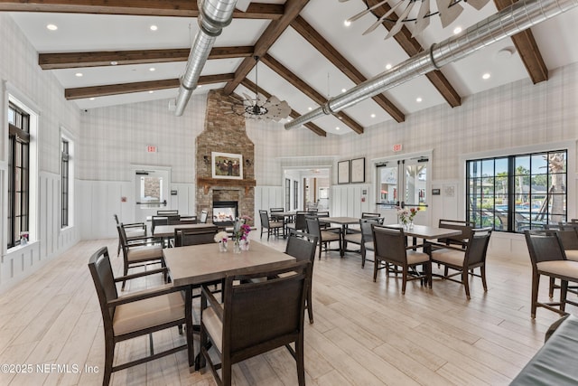 360 Rustic Mill Dr, Saint Augustine, FL 32092 - dining space with wallpapered walls, beam ceiling, high vaulted ceiling, light wood-style floors, and a stone fireplace