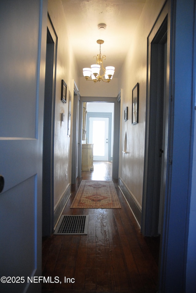 123 Arlington Way, Ormond Beach, FL 32176 - hallway featuring a chandelier, dark wood-style floors, and baseboards