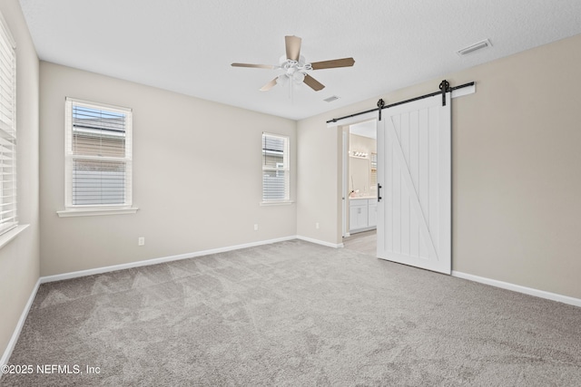 618 Honeycomb Trl, Saint Augustine, FL 32095 - unfurnished bedroom featuring a barn door, carpet flooring, baseboards, and multiple windows