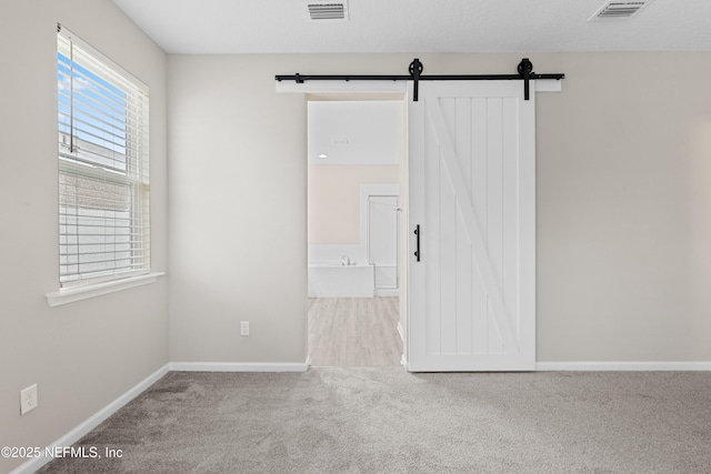 618 Honeycomb Trl, Saint Augustine, FL 32095 - spare room featuring a barn door, carpet floors, and baseboards