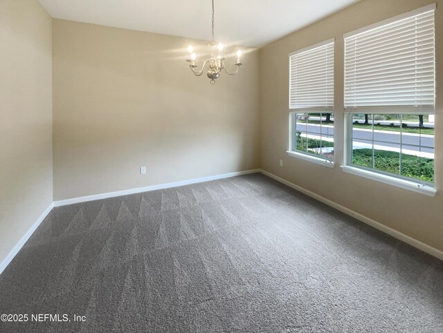 spare room featuring a chandelier, carpet, and baseboards