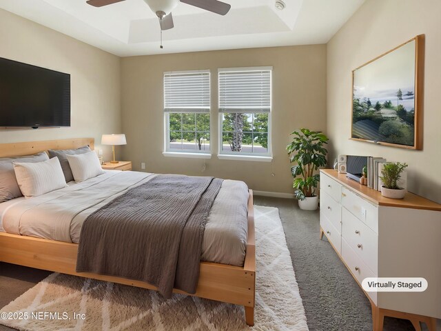 bedroom with a raised ceiling, carpet, baseboards, and ceiling fan