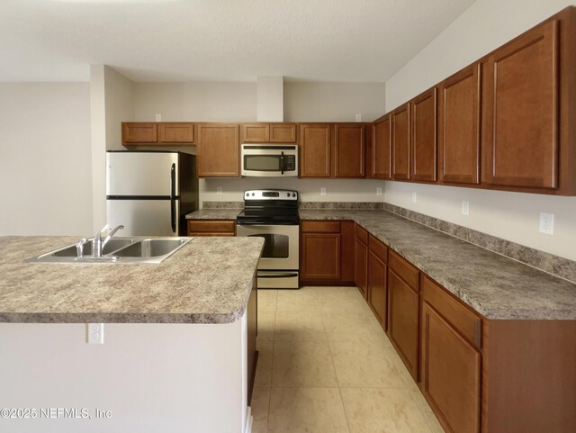 kitchen featuring appliances with stainless steel finishes, a sink, brown cabinets, and light tile patterned floors