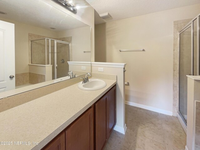 full bathroom with a shower stall, tile patterned floors, vanity, a textured ceiling, and baseboards