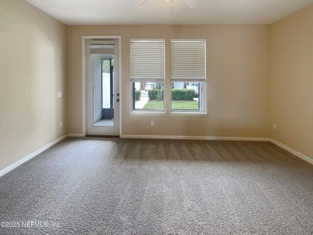 carpeted empty room featuring baseboards and a ceiling fan