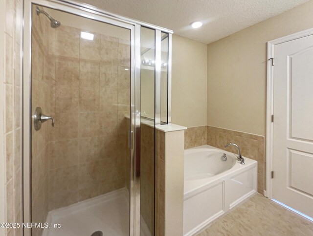 bathroom featuring a garden tub, a stall shower, and a textured ceiling