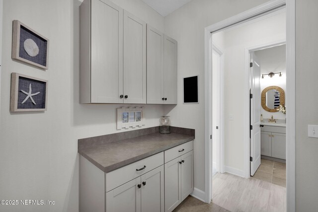 111 Bucktail Ave, Ponte Vedra, FL 32081 - kitchen with dark countertops, a sink, white cabinetry, and baseboards