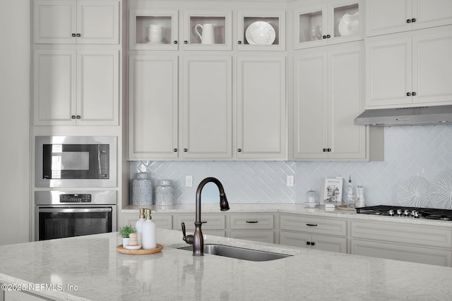 111 Bucktail Ave, Ponte Vedra, FL 32081 - kitchen with stainless steel appliances, under cabinet range hood, a sink, light stone counters, and white cabinets