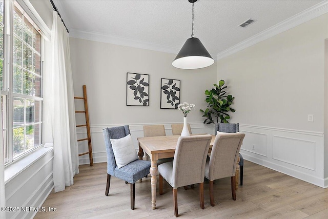 12768 Cattail Pond Cir S, Jacksonville, FL 32224 - dining room with light wood-type flooring, crown molding, a wainscoted wall, and a textured ceiling