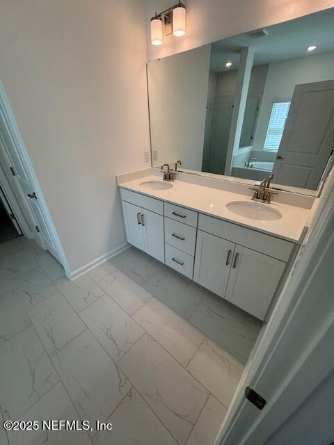 317 Archstone Way, Saint Augustine, FL 32092 - full bath featuring marble look tiles, baseboards, double vanity, a bath, and a stall shower