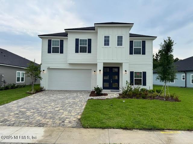 150 Iris Landing Dr, Saint Augustine, FL 32092 - view of front of property with board and batten siding, decorative driveway, a front lawn, an attached garage, and french doors