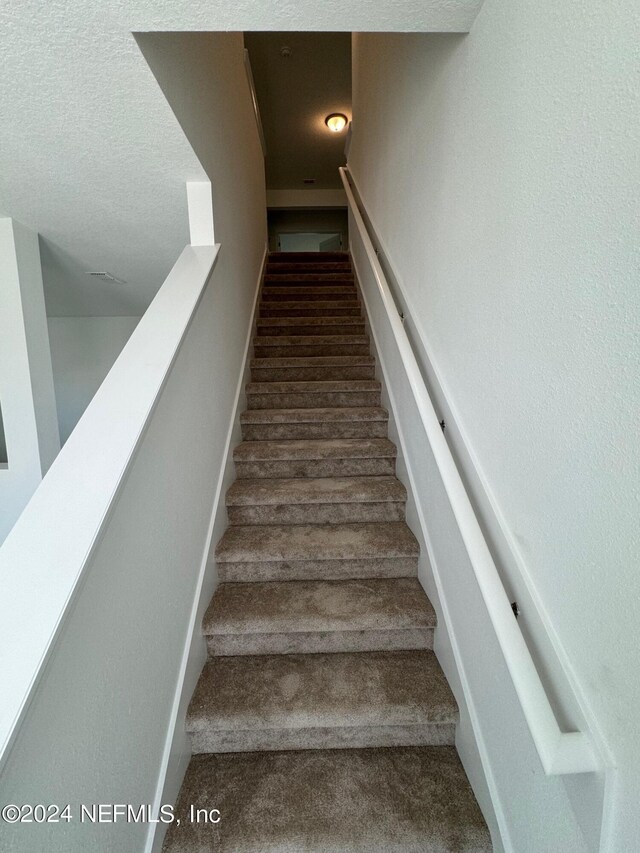 150 Iris Landing Dr, Saint Augustine, FL 32092 - staircase featuring carpet flooring and a textured ceiling