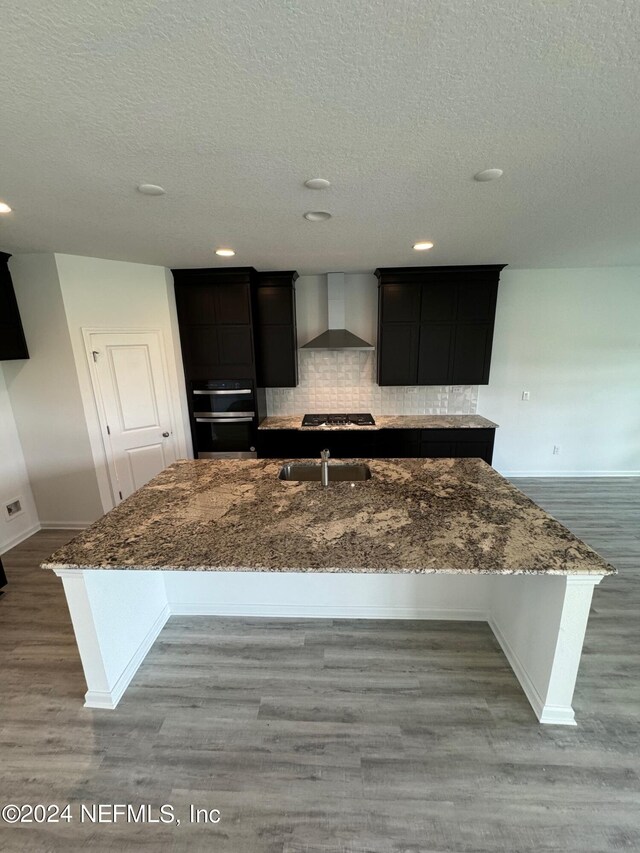 150 Iris Landing Dr, Saint Augustine, FL 32092 - kitchen with baseboards, wall chimney range hood, a sink, dark stone counters, and a textured ceiling
