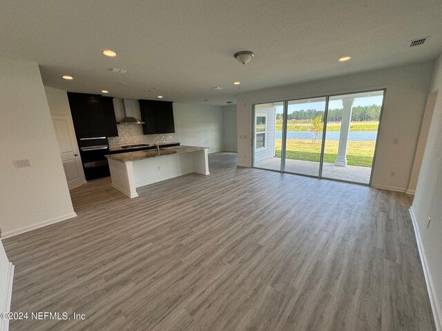 150 Iris Landing Dr, Saint Augustine, FL 32092 - kitchen featuring open floor plan, wall chimney range hood, tasteful backsplash, wood finished floors, and recessed lighting