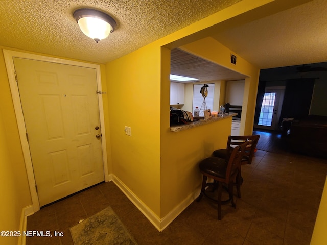 8741 Whispering Pines Dr, Jacksonville, FL 32244 - foyer entrance featuring dark tile patterned floors, a textured ceiling, and baseboards
