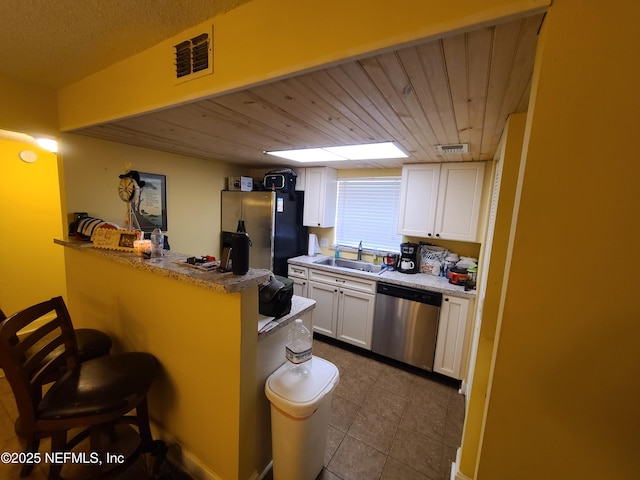 8741 Whispering Pines Dr, Jacksonville, FL 32244 - kitchen featuring appliances with stainless steel finishes, a sink, a kitchen bar, white cabinetry, and a peninsula