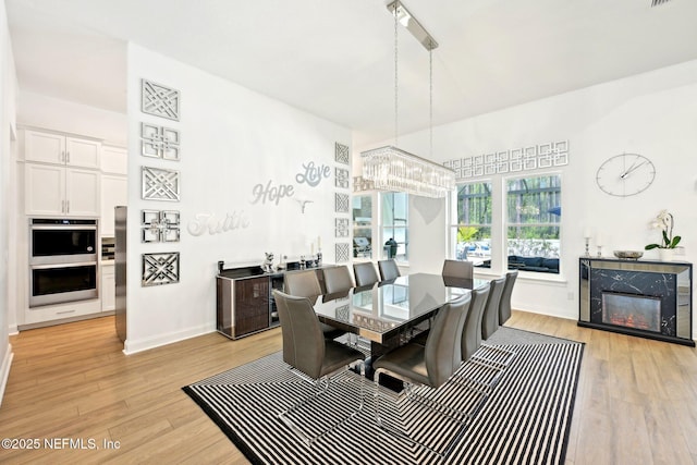 210 Terra Oaks Dr, Saint Johns, FL 32259 - dining area with light wood-style flooring, a chandelier, baseboards, and a high end fireplace