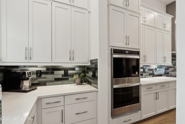 210 Terra Oaks Dr, Saint Johns, FL 32259 - kitchen featuring stainless steel double oven, tasteful backsplash, white cabinetry, light countertops, and light wood-style floors