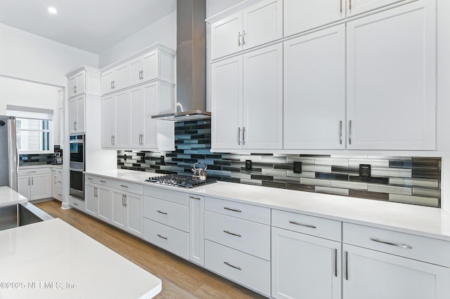 210 Terra Oaks Dr, Saint Johns, FL 32259 - kitchen with appliances with stainless steel finishes, wall chimney range hood, decorative backsplash, light countertops, and light wood-type flooring