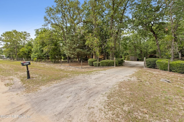 view of dirt / gravel road with view of wooded area