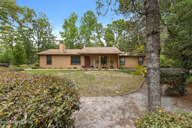 ranch-style home with a porch, a chimney, and a front lawn