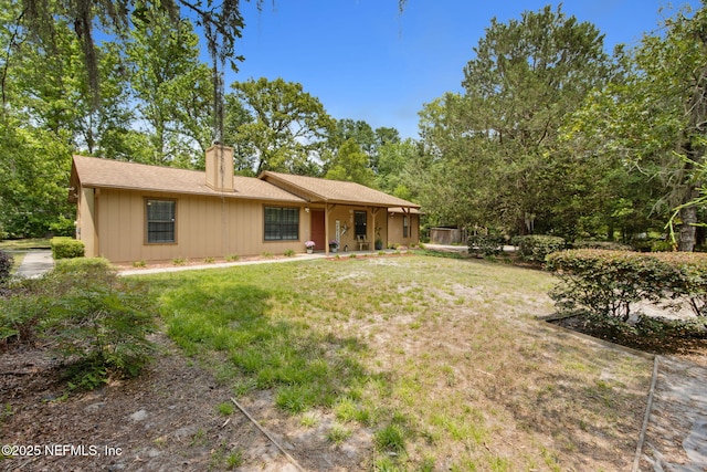 rear view of property featuring a chimney, a yard, and roof with shingles