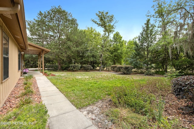 view of grassy yard with view of wooded area