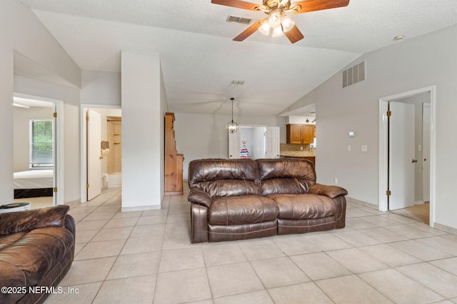 living area featuring lofted ceiling, light tile patterned floors, ceiling fan, and baseboards